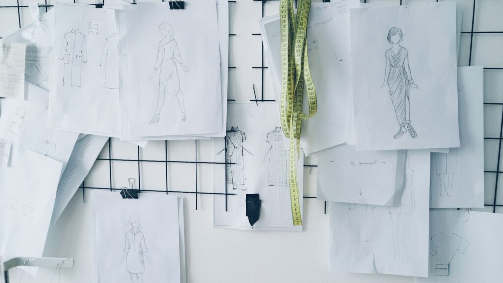 Fashion design sketches pinned to a board with a measuring tape, representing translation for fashion brands