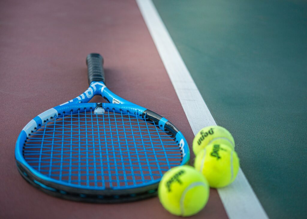 A tennis racket and balls on a court, representing sports content translation into Spanish